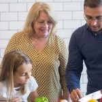A family happily preparing vegetables together in a modern kitchen.