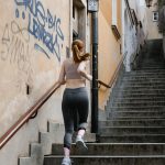 Back view of a female runner exercising on outdoor stairs in an urban setting.