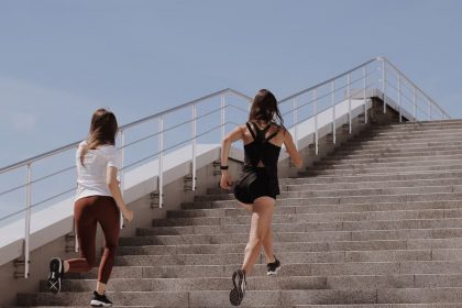 Two women running up stairs outdoors, embodying fitness and wellness.