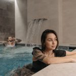 Tattooed woman and man enjoying a modern indoor pool setting, emphasizing relaxation.