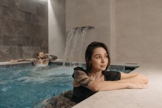 Tattooed woman and man enjoying a modern indoor pool setting, emphasizing relaxation.
