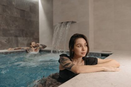 Tattooed woman and man enjoying a modern indoor pool setting, emphasizing relaxation.